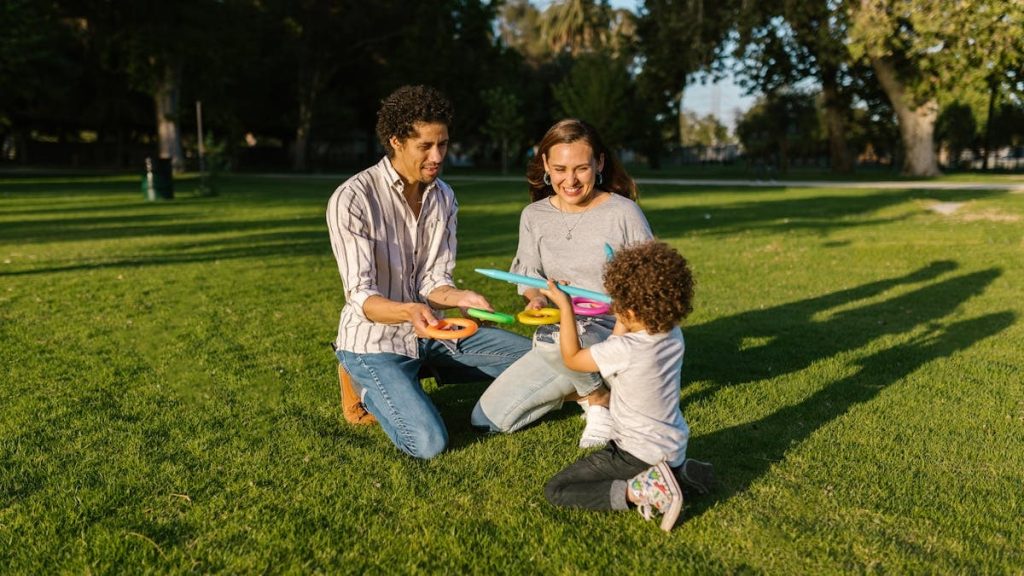 Family playing ring toss together enjoying sunny day in park.